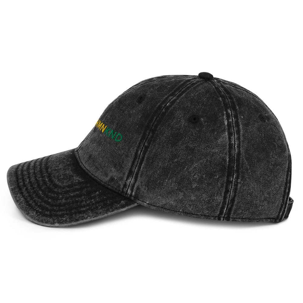 Black distressed baseball cap with "KIND" embroidered in green and yellow on the front.