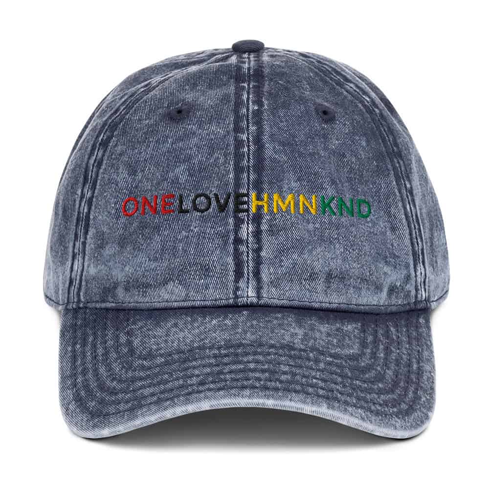 "OneLoveHMNKND" distressed denim baseball cap with colorful embroidered message for unity and love.