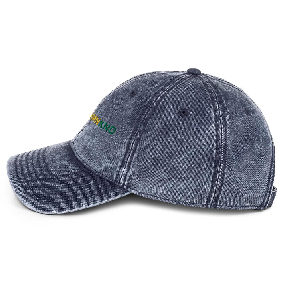 Distressed denim baseball cap with "BE A KIND" embroidery in rainbow colors. Adjustable strap, stylish and eco-friendly accessory.